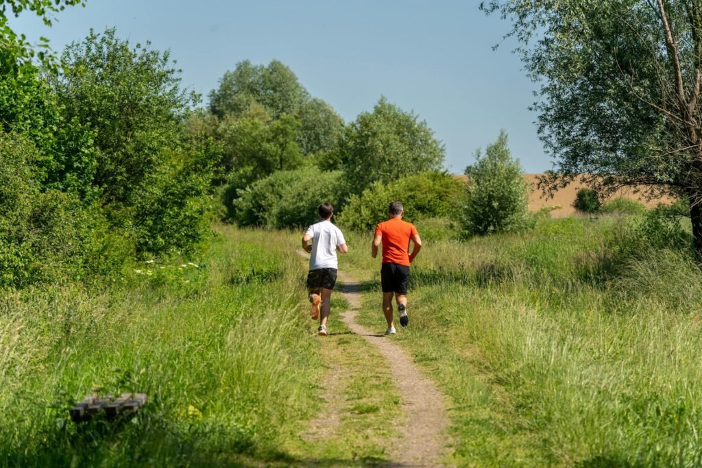 Two men jogging on a scenic forest trail surrounded by lush greenery in Garešnica, Croatia.