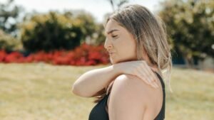 A woman in a black top indicating her shoulder hurts